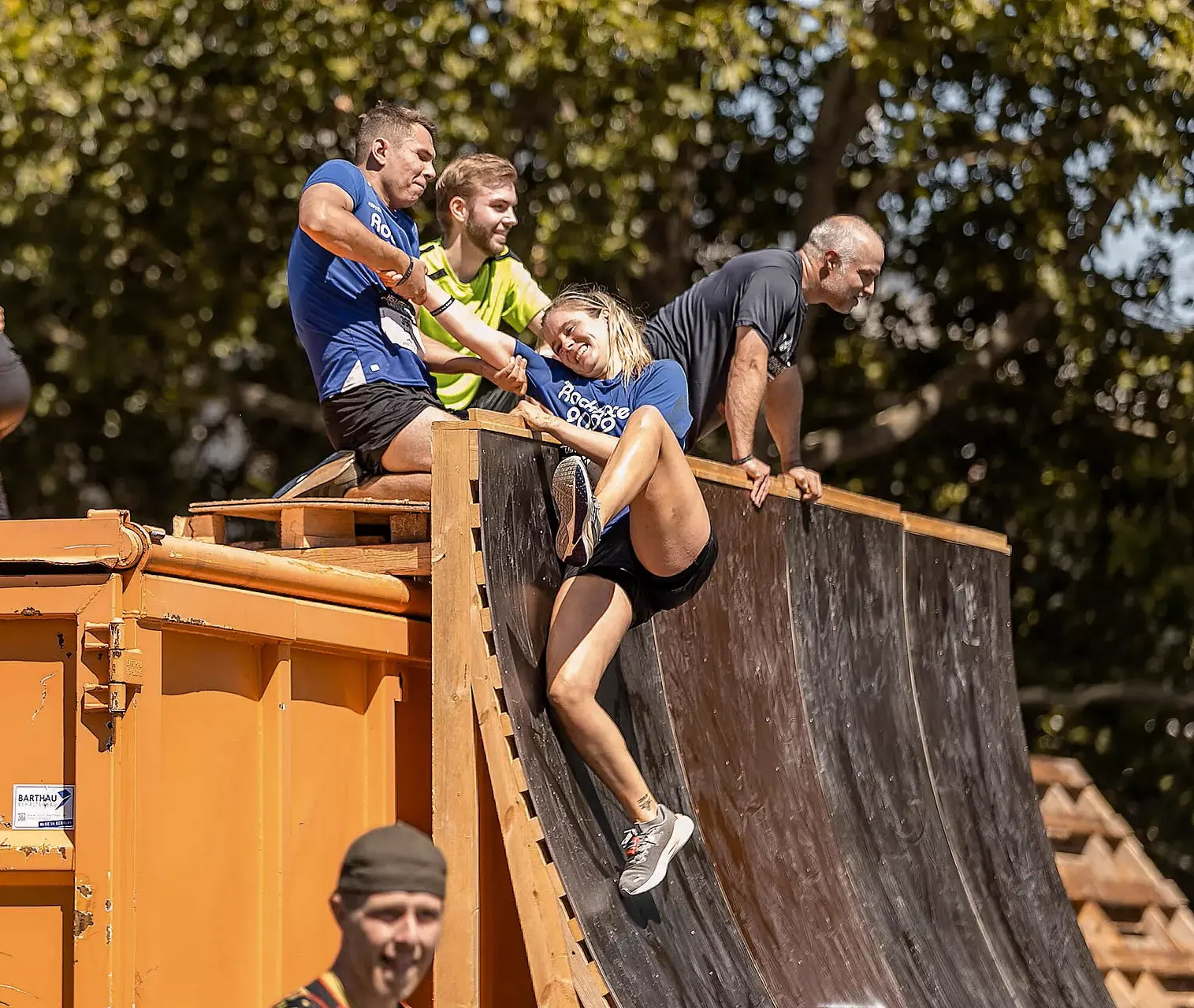 Teilnehmende helfen sich gegenseitig eine hölzerne Halfpipe hinauf